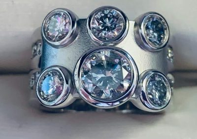 Elegant diamond ring with multiple round-cut diamonds in a modern setting.