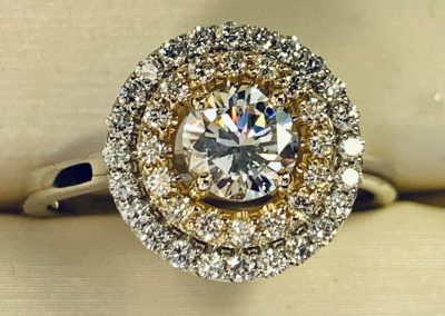 Beautiful diamond ring with gold setting and surrounding smaller diamonds.